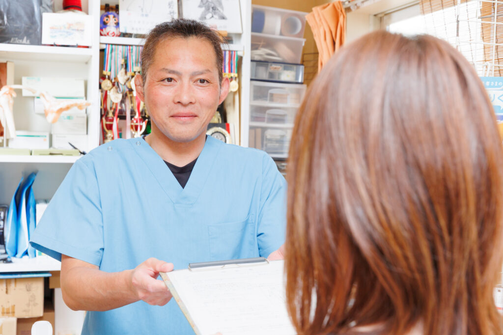 受付で問診票を渡している